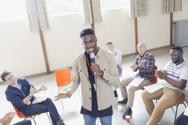 Man with microphone leading group therapy - CAIF22599