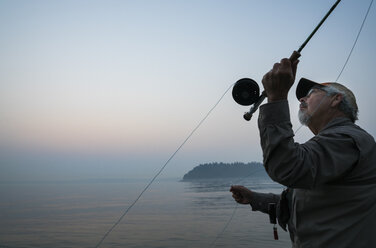 Älterer kaukasischer Mann beim Fliegenfischen auf Lachs und Meerforelle an der Küste - MINF09878
