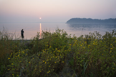 Silhouette of fisherman fly fishing for salmon and searun cutthroat trout - MINF09884