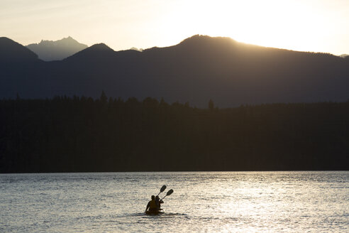 Ein Paar, das in einem Kajak sitzt und auf dem Puget Sound in der Nähe der Olympic Mountains im Bundesstaat Washington, USA, paddelt. - MINF09897