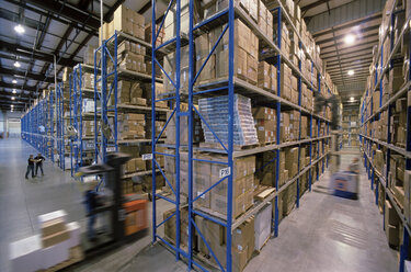 Überblick über ein großes industrielles Auslieferungslager, in dem Produkte in Kartons auf Förderbändern und Regalen gelagert werden. - MINF09951