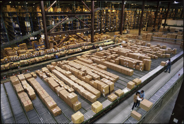 Overview of a large industrial distribution warehouse storing products in cardboard boxes on conveyor belts and racks. - MINF09952