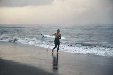 Indonesien, Bali, Canggu Strand, Surfer mit Surfbrett am Strand - KNTF02598