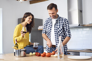 Zärtliches Paar in der Küche, das gemeinsam Spaghetti zubereitet und roten Wein trinkt - BSZF00844