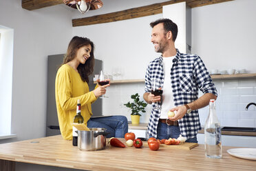 Zärtliches Paar in der Küche, das gemeinsam Spaghetti zubereitet und roten Wein trinkt - BSZF00846