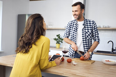 Affectionate couple in kitchen, preparing spaghetti toghether, using digital tablet - BSZF00853