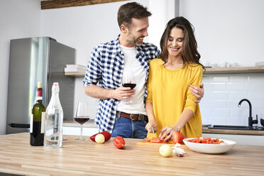 Affectionate couple in kitchen, preparing spaghetti toghether, drinking red wein - BSZF00860