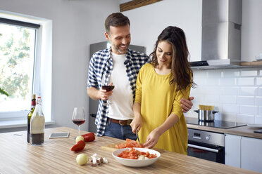 Zärtliches Paar in der Küche, das gemeinsam Spaghetti zubereitet und roten Wein trinkt - BSZF00861