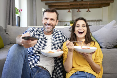 Ehepaar sitzt im Wohnzimmer, isst Spaghetti und sieht fern - BSZF00872