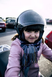 Portrait of smiling little girl on a motorcycle wearing helmet and pink leather jacket - MGOF03925