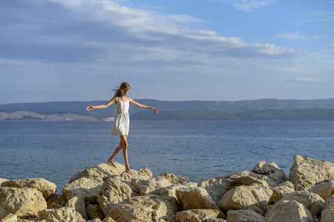 Kroatien, Lokva Rogoznica, Mädchen balanciert barfuß auf Felsen, lizenzfreies Stockfoto