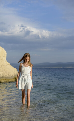 Kroatien, Lokva Rogoznica, Mädchen watet im Wasser in der Nähe des Strandes, lizenzfreies Stockfoto