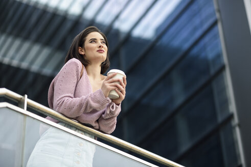 Portrait of smiling young woman with coffee to go looking at distance - JSMF00727
