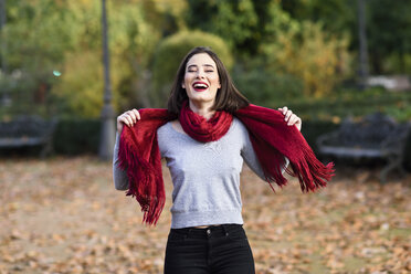 Portrait of laughing young woman wearing red scarf in autumn - JSMF00730