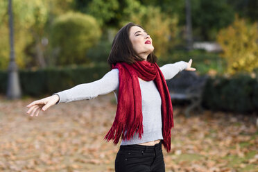 Happy young woman wearing red scarf in autumn - JSMF00731