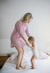 Mutter spielt mit Kleinkind Sohn auf Bett zu Hause - HAPF02816