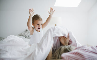 Glückliches Kleinkind Sohn spielt mit Mutter im Bett zu Hause - HAPF02818