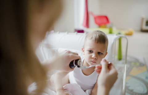 Mutter gibt ihrem kleinen Sohn zu Hause Medikamente, lizenzfreies Stockfoto