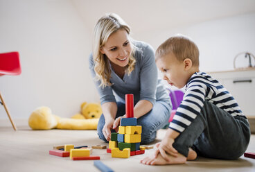 Glückliche Mutter und ihr kleiner Sohn spielen zu Hause mit Bauklötzen - HAPF02827