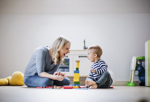 Glückliche Mutter und ihr kleiner Sohn spielen zu Hause mit Bauklötzen - HAPF02828