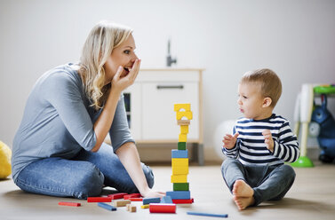 Glückliche Mutter und ihr kleiner Sohn spielen zu Hause mit Bauklötzen - HAPF02829