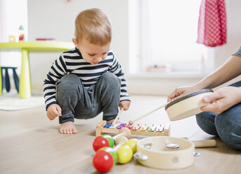 Mother and toddler son playing with musical instruments at home - HAPF02831