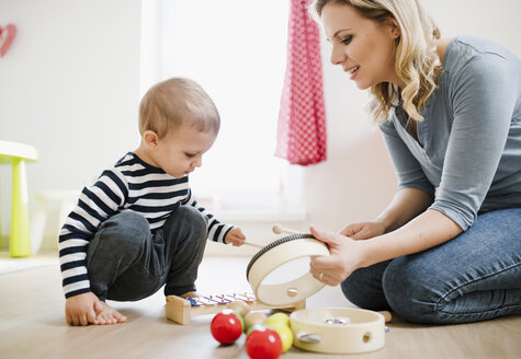 Mutter und kleiner Sohn spielen zu Hause mit Musikinstrumenten - HAPF02832