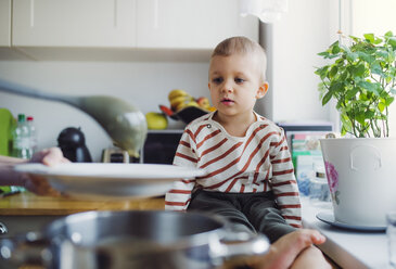 Toddler boy watching mother preparing food in kitchen at home - HAPF02836