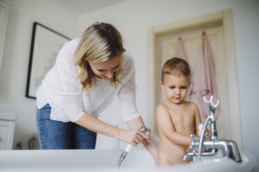 Mother washing toddler son in bathtub at home - HAPF02837