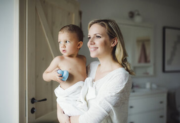 Smiling mother holding toddler son in bathroom at home - HAPF02840