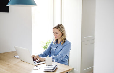 Frau mit Laptop bei der Arbeit zu Hause - HAPF02856