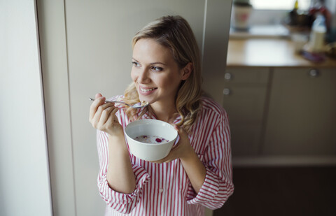 Lächelnde Frau beim morgendlichen Frühstück zu Hause, lizenzfreies Stockfoto