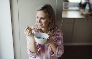 Smiling woman having breakfast in the morning at home - HAPF02863