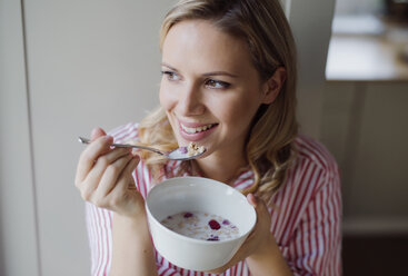 Smiling woman having breakfast in the morning at home - HAPF02864
