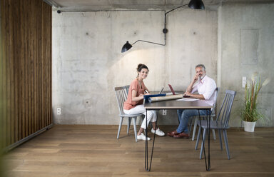 Smiling businessman and businesswoman working in a loft - FKF03170