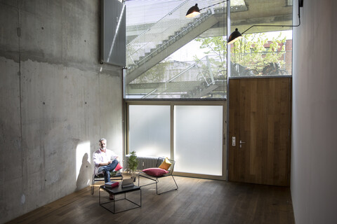 Geschäftsmann sitzt in einem Loft an einer Betonwand und macht eine Pause, lizenzfreies Stockfoto