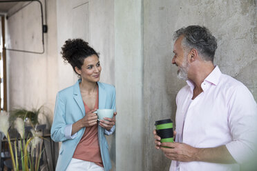 Smiling businessman and businesswoman having a coffee break in a loft - FKF03217