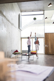 Lässiger Geschäftsmann und Geschäftsfrau spielen Basketball in einem Loft - FKF03229