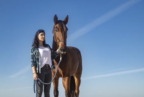 Frau mit Pferd unter blauem Himmel, lizenzfreies Stockfoto