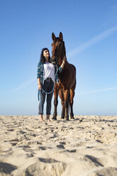 Frau mit Pferd im Sand stehend - KBF00372