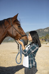 Spanien, Tarifa, Frau küsst Pferd am Strand - KBF00376