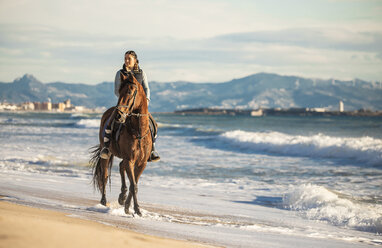 Spanien, Tarifa, Frau reitet Pferd am Strand - KBF00381