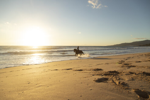 Spain, Tarifa, woman riding horse on the beach at sunset - KBF00388