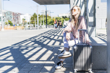 Spanien, Barcelona, junge Frau mit Trolley-Tasche wartet am Bahnhof - GIOF05467