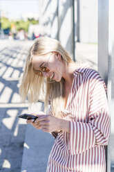 Blonde junge Frau benutzt Smartphone im Freien - GIOF05469