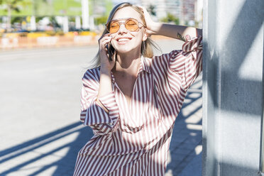 Porträt einer glücklichen jungen Frau beim Telefonieren im Freien - GIOF05470