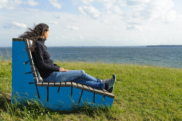 Dänemark, Jütland, Sonderborg, Frau sitzt auf Parkbank in der Bucht von Sonderborg - UMF00921