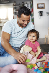 Smiling father and baby girl playing with building blocks at home - ABIF01081