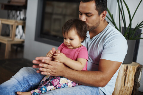 Zärtlicher Vater umarmt und küsst seine Tochter zu Hause, lizenzfreies Stockfoto