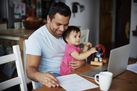 Vater mit kleinem Mädchen benutzt Laptop auf dem Tisch zu Hause, lizenzfreies Stockfoto